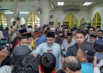 ANWAR Ibrahim menyantuni jemaah selepas menunaikan solat Jumaat di Masjid Kota Damansara di sini, hari ini. -UTUSAN/FARIZ RUSADIO