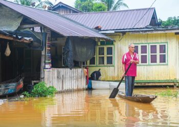 PENDUDUK kampung, Abdullah Syafie, 77, meredah banjir menaiki perahu untuk pulang melihat keadaan rumahnya selepas dinaiki air ketika tinjauan di Kampung Matang. -UTUSAN/PUQTRA HAIRRY