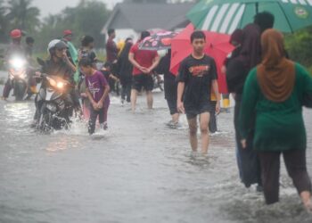 PENDUDUK kampung melalui jalan yang digenangi air berikutan hujan lebat sejak beberapa hari lepas semasa tinjauan di Kampung Atas Tol, baru-baru ini. -UTUSAN/PUQTRA HAIRRY