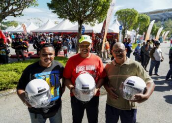 PARA pengunjung menunjukkan topi keledar baharu yang ditukar secara percuma sempena Program Setahun Bersama Kerajaan MADANI di pekarangan Stadium Nasional Bukit Jalil (SNBJ) di sini, hari ini. -UTUSAN/FARIZ RUSADIO