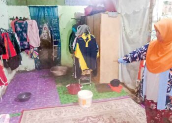 MAZIAH Yahya menunjukkan beberapa buah baldi yang diletakkan untuk menahan air ekoran bumbung yang bocor di rumahnya di Felda Kota Gelanggi Dua di Jerantut, Pahang. – UTUSAN/HARIS FADILAH AHMAD