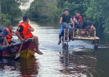 MOHD. Kalmiru Zuhairi Abdullah menunggang motosikal yang diubah suai untuk membawa mangsa banjir 
di Kampung Bawah Lembah, Gual Periok, Rantau Panjang, Kelantan. – UTUSAN/YATIMIN ABDULLAH