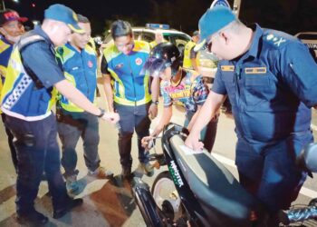 MUHAMMAD FIRDAUS Shariff (kanan) melihat anggota JPJ memeriksa seorang penunggang motosikal di Malim, Melaka. 
– UTUSAN/AMRAN MULUP
