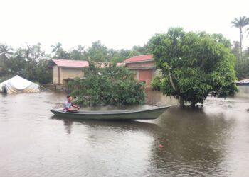 MUHAMAD Shafik Mohd. Zin terpaksa menaiki perahu untuk memeriksa keadaan rumahnya di Kampung Tersang, Rantau Panjang, Kelantan. UTUSAN/ROSMIZAN RESDI