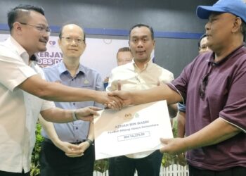 ZULKARNAIN Kamisan (dua dari kanan) menyaksikan Pengerusi Jawatankuasa Belia, Sukan, Pembangunan Usahawan, Koperasi dan Sumber Manusia Negeri Johor, Mohd Hairi Mad Shah (kiri) menyampaikan faedah caruman kepada Azhan Basri yang mengalami kecedereaan patah paha kanan akibat kemalangan lori ketika hadir dalam Karnival Kerjaya Myfuturejobs dan Pendidikan Batu Pahat di Dewan Taman Industri Sri Sulong di Batu Pahat hari ini.
