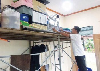 MOHD. Nordin Yusof menyimpan barang kelengkapan rumah di atas rak yang dibinanya bagi mengelak ditenggelami air banjir di Kampung Tersang, Rantau Panjang, Kelantan. – UTUSAN/ROSMIZAN RESDI.