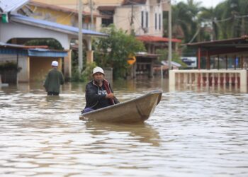 SEORANG penduduk mengayuh perahu untuk mematau banjir yang melanda kawasan di Rantau Panjang, Kelantan semalam-UTUSAN/KAMARUL BISMI KAMARUZAMAN.