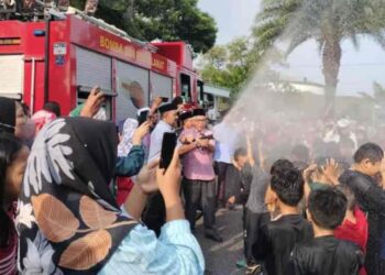 HASSAN  (tengah) menyembur air kepada kanak-kanak yang mengikuti Program Khatan Perdana Anjuran Pejabat Parlimen Pasir Gudang di Masjid Bandar Permas Jaya, Johor Bahru, hari ini.