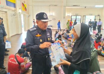 KETUA Polis Kelantan Datuk Muhamad Zaki Harun (kiri) menyerahkan sumbangan semasa menyantuni mangsa banjir yang masih berlindung di PPS SK Sri Rantau Panjang, Kelantan hari ini-UTUSAN/ROHANA ISMAIL.