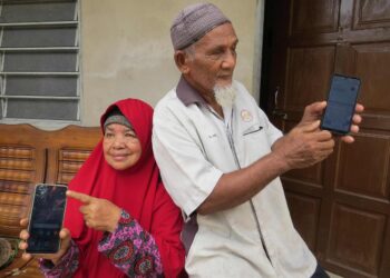 CHE Hussain @ Che Ahmad Che Kob (kanan) menunjukkan telefonnya yang tidak mempunyai rangkaian internet di rumahnya di Kampung Sungai Bayu Dalam, Gua Musang, Kelantan. – Utusan/AIMUNI TUAN LAH