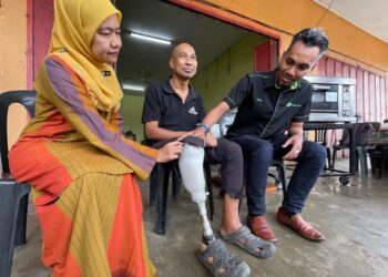 NORA Yaacub (kiri) dan Mohamad Rosli Mustapai (kanan) melihat kaki palsu yang disumbangkan Perkeso kepada Mohd. Azman di Kampung Panjang Perupuk, Bachok, Kelantan hari ini. UTUSAN/TOREK SULONG