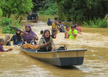 MAZITA Mamat (depan) menaiki perahu selepas jambatan Sungai Kerak di Kampung Limau Kasturi, Gua Musang, Kelantan ditenggelami banjir.-UTUSAN/AIMUNI TUAN LAH.