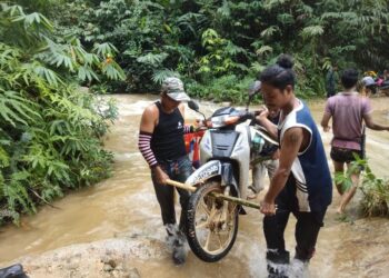 BEBERAPA Orang Penduduk Orang Asli terpaksa mengangkat motosikal selepas meredah sungai untuk ke Bandar Gua Musang, Kelantan. UTUSAN/IHSAN ORANG ASLI