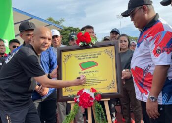ARMIZAN Mohd. Ali (kiri) menandatangani plak perasmian Trek Larian getah sintetik Padang Pekan Papar, Sabah.