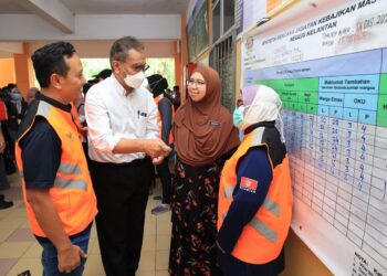 DR. Dzulkefly Ahmad (dua dari kiri) beramah mesra bersama kakitangan JKM semasa lawatan di PPS Sekolah Menengah Kebangsaan Baroh Pial, Rantau Panjang, Kelantan. -UTUSAN/KAMARUL BISMI KAMARUZAMAN