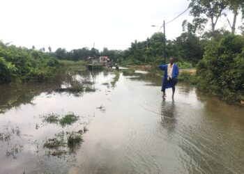 SEORANG penduduk menunjukkan laluan utama yang digenangi air sejak seminggu lalu di Kampung
Serongga, Pasir Mas, Kelantan. – UTUSAN/ROSMIZAN RESDI