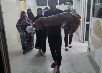 Nur Afiah Sumayyah yang berusia 18 bulan dipangku bapanya, Mohammad Sulaiman selepas selesai urusan bedah siasat di Unit Forensik Hospital Dungun, malam tadi.