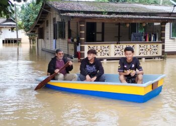 SYUKRI Dollah (kiri) menaiki bot fiber yang dibeli bersama anak-anaknya selepas kediaman mereka dinaiki air dalam kejadian banjir di Kampung Buluh, Setiu, hari ini. - UTUSAN/WAN ZURATIKAH IFFAH WAN ZULKIFLI