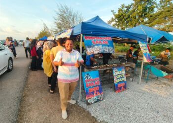 MUHAMMAD Hilmee Roslan berdiri di depan gerai siput bakar yang dikerumuni pengunjung di jalan pesisir laut Sungai Baru, Kangar, Perlis baru-baru ini- UTUSAN/SYED AZLAN SAYID HIZAR