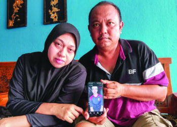 PUTRAWIRAWAN Irwan (kanan) bersama Nor Ain Zakaria menunjukkan gambar Allahyarham Putra Norsyaqir Putrawirawan ketika ditemui di kediaman mereka di Batu Berendam, Melaka. - UTUSAN/MUHAMMAD SHAHIZAM TAZALI