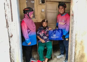 JASRI Kasim (kanan) menyerahkan bakul makanan kepada pesakit angin ahmar di Jalan Gajah Mati, Kota Bharu, Kelantan. .- UTUSAN/ ROSLJZA MOHAMED