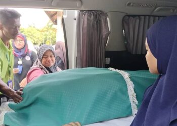 NORHANA  Osman melihat jenazah suaminya sebelum dibawa pulang ke Kampung Simpang di Taiping untuk dikebumikan. - UTUSAN/WAT KAMAL ABAS