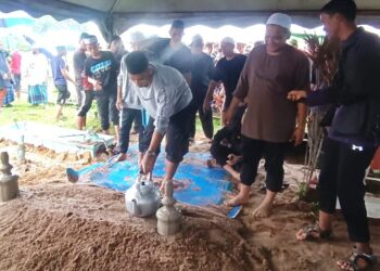 SAFAWI menyiram pusara bapanya, Allahyarham Rasid Sulong yang dikebumikan di Tanah Perkuburan Islam Syed Yahya, Dungun, petang ini. - UTUSAN/NIK NUR IZZATUL HAZWANI NIK ADNAN
