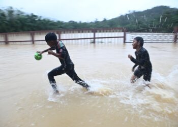 DUA kanak-kanak bermain air dalam kejadian banjir di Kampung Pengkalan Ajal, Hulu Terengganu, hari ini. - UTUSAN/PUQTRA HAIRRY ROSLI