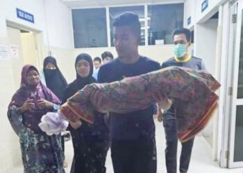 MAYAT Afiah Sumayyah berusia 18 bulan dipangku bapanya, Mohammad Sulaiman selepas selesai urusan bedah siasat di Unit Forensik Hospital Dungun, semalam. - UTUSAN/ NIK NUR IZZATUL HAZWANI NIK ADNAN