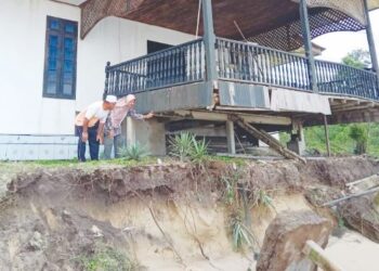 HAMIDAH Hassan (kanan) melihat anjung rumahnya yang runtuh selepas berlaku hakisan pantai di Kampung Mengabang Telong, Batu Rakit, Kuala Nerus, semalam. – UTUSAN/TENGKU DANISH BAHRI TENGKU YUSOFF