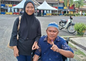 MOHAMAD Boto dibantu anaknya, Siti Musliha Azlina mengundi di pusat mengundi di SK Kampung Baru Kerteh, hari ini. - UTUSAN/NIK NUR IZZATUL HAZWANI NIK ADNAN