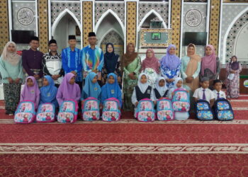 TUNKU Puteri Intan Safinaz Sultan Abdul Halim Mu’adzam Shah (lima dari kanan) bergambar kenangan dengan sebahagian pelajar sekolah ketika Program Santuni Asnaf di Masjid Tunku Intan Safinaz, Kampung Lanai, Baling.