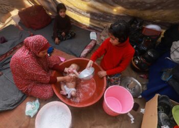 SEORANG wanita memandikan bayinya di dalam besen di khemah penduduk Palestin di Rafah, selatan Semenanjung Gaza. - AFP