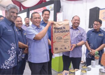 AMINUDDIN Harun (tiga dari kiri) dan Zaiviji Ismail (kiri) menunjukkan simen pukal di bawah inisiatif Skim Simen Rahmah pada Majlis Perasmian Kilang Bancuh Konkrit UPC di Sendayan, Seremban, semalam.