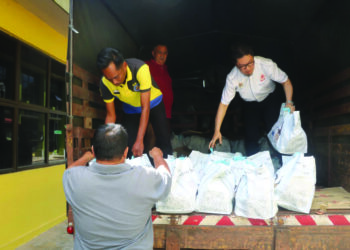 PAUL LEE Kok Sun (kanan) membantu mengangkat bakul makanan untuk disumbangkan kepada mangsa banjir di pekarangan Pejabat Tanah dan Daerah Raub di Raub, Pahang. - UTUSAN/SALEHUDIN MAT RASAD