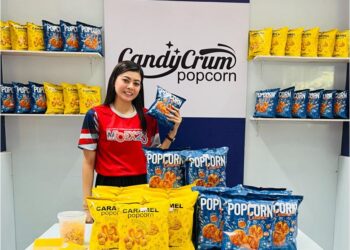 NORAIN Khairuddin menunjukkan bertih jagung jenama Candy Crum Popcorn yang dikeluarkan oleh syarikatnya di Bahau, Negeri Sembilan.