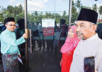 ADIB Amat Mustakim menyelitkan memorandum bantahan di celah pintu Pejabat Pusat Khidmat Rakyat Parlimen Tanjong Karang di Kuala Selangor, Selangor, semalam. - UTUSAN/ SADDAM YUSOFF
