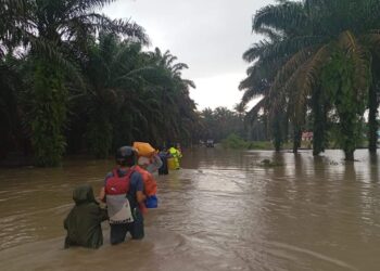 Penduduk di Kampung Contoh  meredah air ketika berpindah ke Pusat Pemindahan Sementara di Dewan Serbaguna Majlis Perbandaran Kluang (MPK) di Kahang.