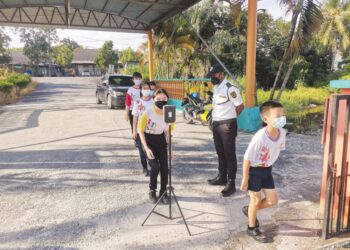 MURID memakai pelitup muka dan menjalani pemeriksaan suhu badan sebelum masuk ke sekolah di sebuah sekolah rendah di Bagan Datuk, Perak. – UTUSAN/AIN SAFRE BIDIN