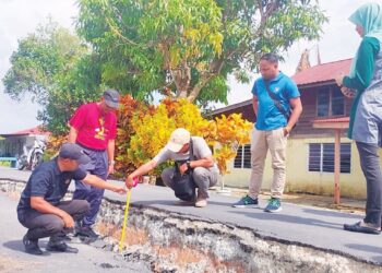 ABDUL Yunus Jamahri (kiri) menunjukkan keadaan jalan yang mendap di Kampung Parit 30,  Kuala Kurau di Parit Buntar, Perak semalam. – UTUSAN/WAT KAMAL ABAS