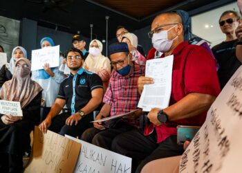 Hishamuddin Hashim (duduk, dua dari kiri) menyaksikan salah seorang mangsa penipuan pelaburan membabitkan kerugian sebanyak RM2.8 juta menunjukkan laporan polis yang dibuat dalam sidang akhbar  di Sungai Besi, semalam. -MINGGUAN/ MUHAMAD IQBAL ROSLI