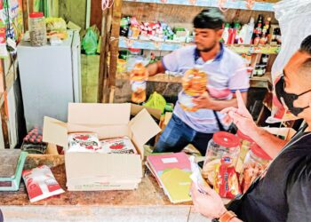 Penjaga kedai mengeluarkan minyak bersubsidi semasa Penguat Kuasa KPDN Melaka melakukan serbuan di sebuah kedai runcit haram ‘perkampungan’ Bangladesh dalam pusat pelancongan ketika operasi di Alor Gajah, Melaka, malam kelmarin. – UTUSAN/SYAFEEQ AHMAD