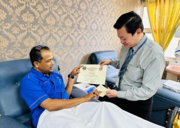 CHE Adam A Rahman menerima sijil sijil pengesahan misi solo 'Derma Darah Tanpa Sempadan' daripada Ketua Jabatan Perubatan Transfusi HSNZ, Dr. Muhaimin Kambali di HSNZ, Kuala Terengganu, hari ini. - UTUSAN/KAMALIZA KAMARUDDIN