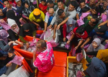 ORANG ramai berasak-asak membeli ikan siakap yang dijual pada harga 90 sen seekor  di Kampung Kuala Ibai, Kuala Terengganu, hari ini. - UTUSAN/PUQTRA HAIRRY ROSLI