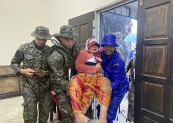 ANGGOTA APM dan tentera membantu memindahkan seorang mangsa ke PPS selepas kediamannya di Kampung Tersusun Seri Delima, Kota Tinggi dinaiki air