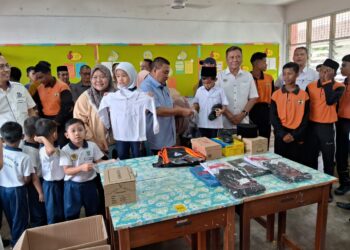 PENGERUSI YPM, Datuk Seri Ismail Mohamed Said (tengah) menyampaikan bantuan persekolahan kepada seorang pelajar sambil diperhatikan Ramlan Harun di SMK Jubli Perak Sultan Haji Ahmad Shah, Kuala Tahan di Jerantut, Pahang. - UTUSAN/SALEHUDIN MAT RASAD