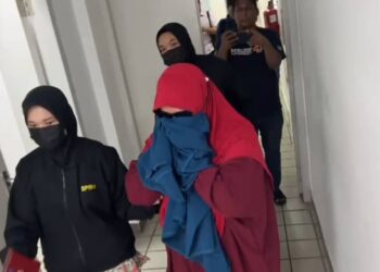 ROSLILAWATI Mukhtar (kanan) yang mengaku salah memalsukan permohonan bantuan persekolahan dibawa keluar dari Mahkamah Sesyen Kuala Terengganu, hari ini. - UTUSAN/TENGKU DANISH BAHRI TENGKU YUSOFF