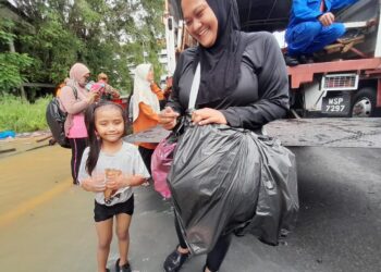 NOORDIYANA Zakaria bersama anaknya yang diselamatkan pasukan penyelamat selepas terperangkap dalam kejadian banjir di kediamannya di Taman Kemang, Kota Tinggi.