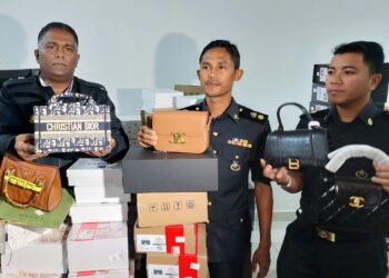 S. JEGAN (kiri) menunjukkan sebahagian daripada barangan tiruan berjenama terkenal yang dirampas dalam satu serbuan di sebuah kediaman elit di Simpang Ampat, SPS, Pulau Pinang, hari ini.