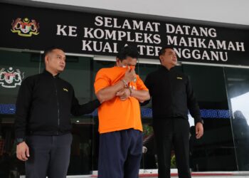 SEORANG pengurus besar lembaga pertubuhan (tengah) yang didakwa melakukan salah guna kuasa dibawa keluar dari Mahkamah Majistret Kuala Terengganu, hari ini. - UTUSAN/TENGKU DANISH BAHRI TENGKU YUSOFF